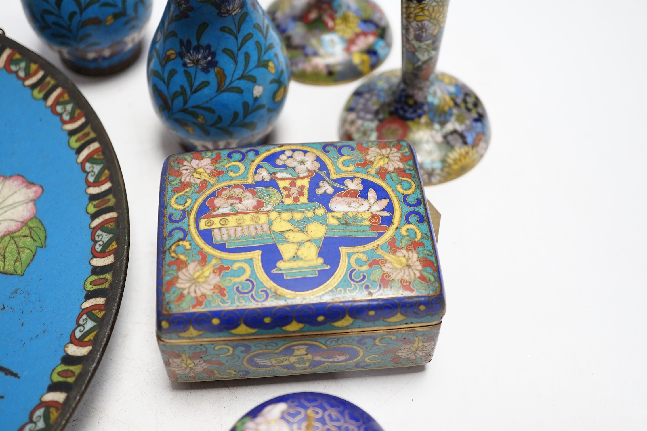 Seven Chinese or Japanese cloisonné enamel items including a pair of candlesticks, 15cm high, a charger, two boxes and a pair of vases